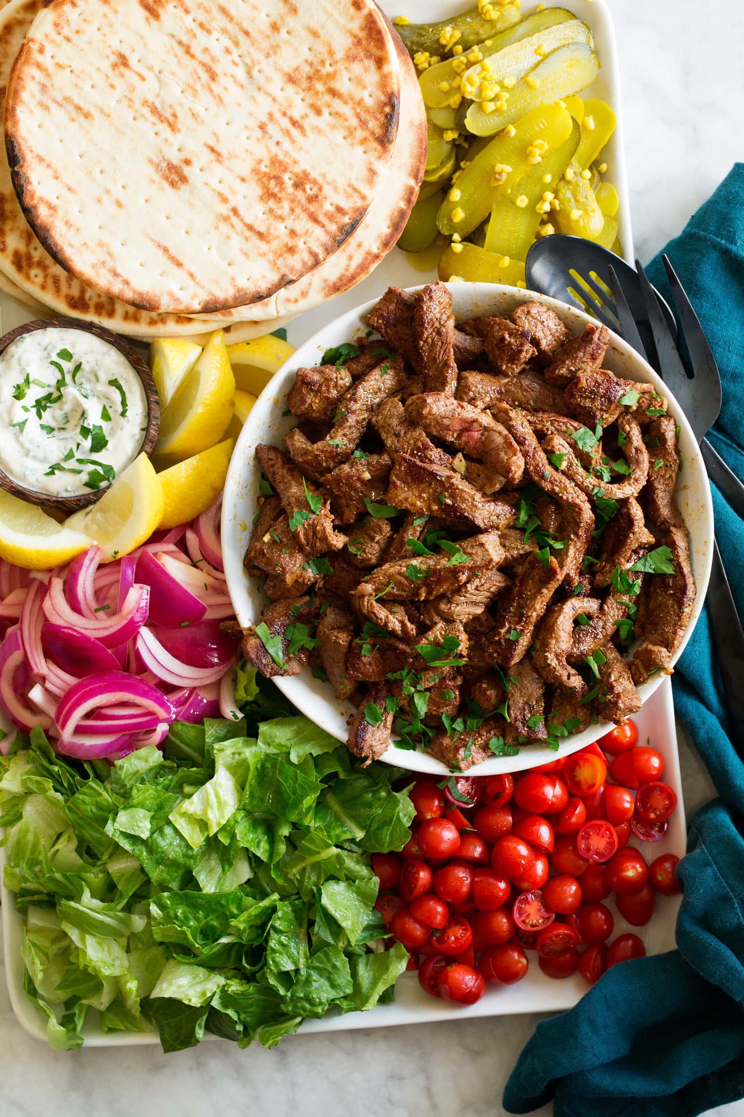 Seared beef shawarma strips shown on a platter with serving suggestions.