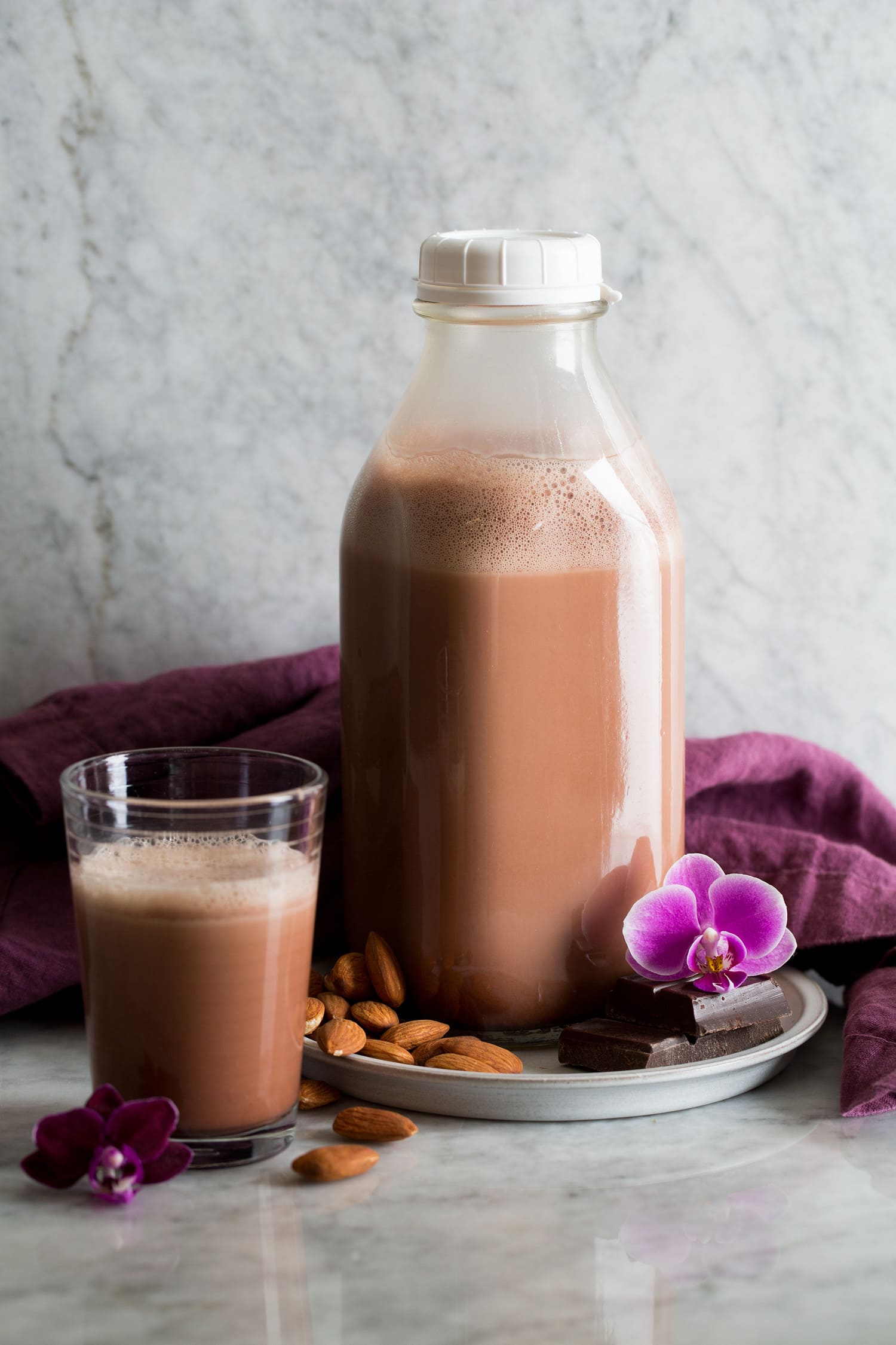 Homemade Chocolate Almond Milk. Shown in a glass milk jar with a cup of it to the side.