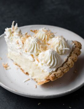 Single slice of coconut cream pie on a white dessert plate.