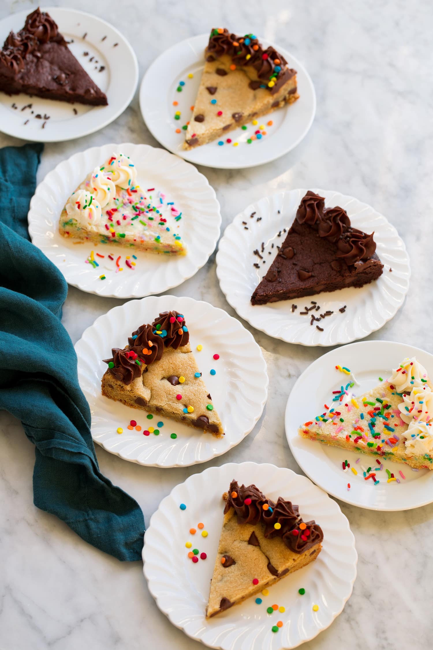 Slices of various flavors of cookie cakes on dessert plates.