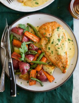 Honey mustard chicken shown with a serving suggestion of roasted vegetables on a serving plate.