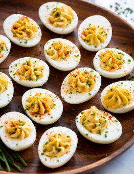 Deviled eggs on a wooden serving platter.