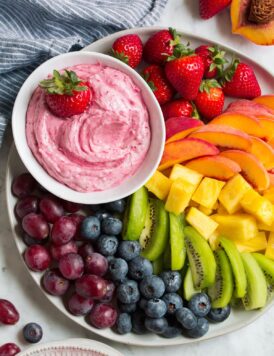 Easy cream cheese fruit dip in a bowl on a serving platter with fruit.