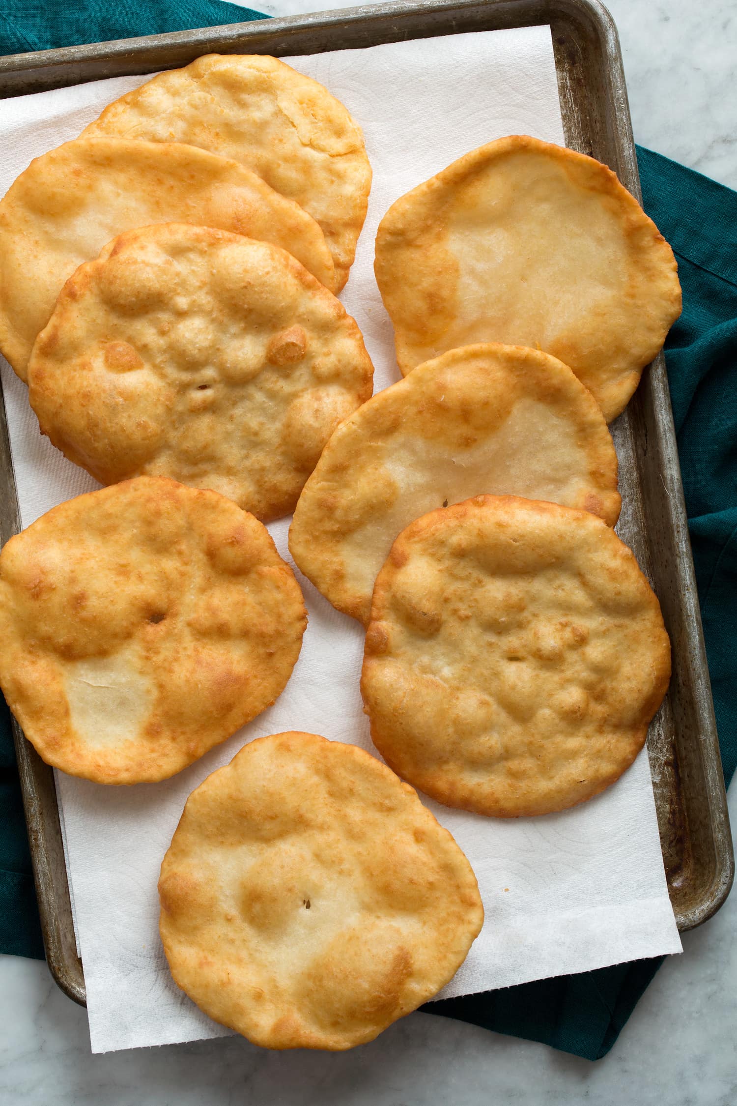 Overhead photo of fry bread draining on paper towel lined baking dish.