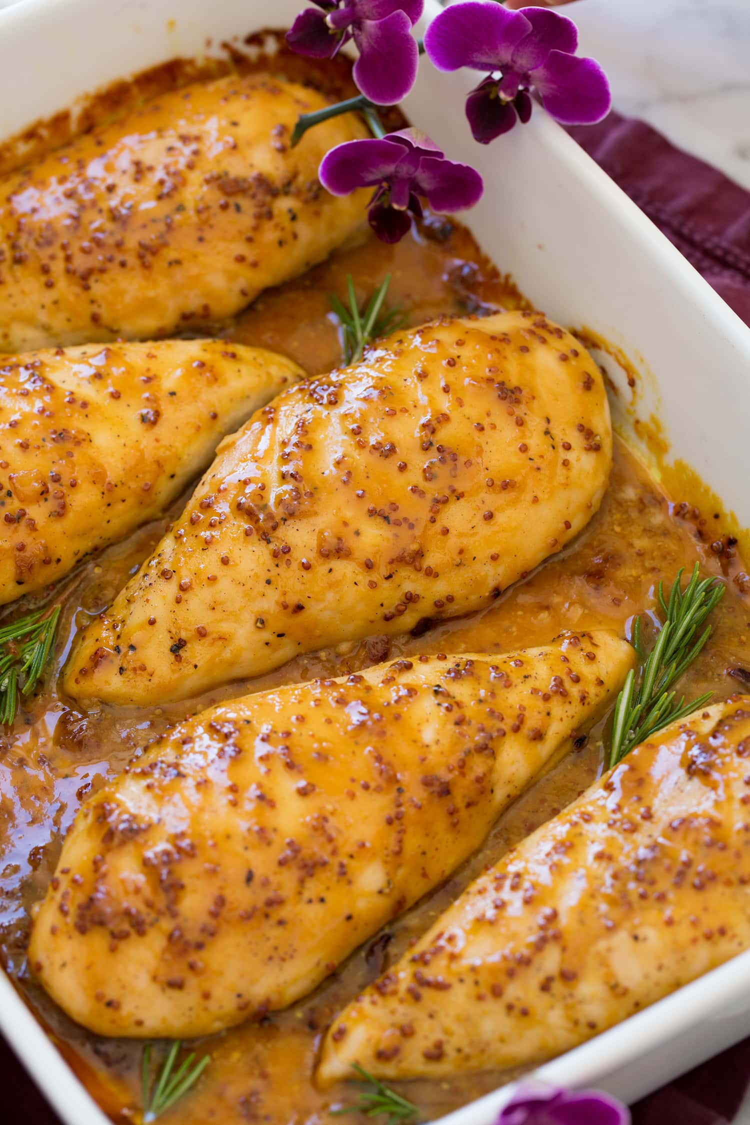 Close up photo of honey mustard chicken breast in baking dish.