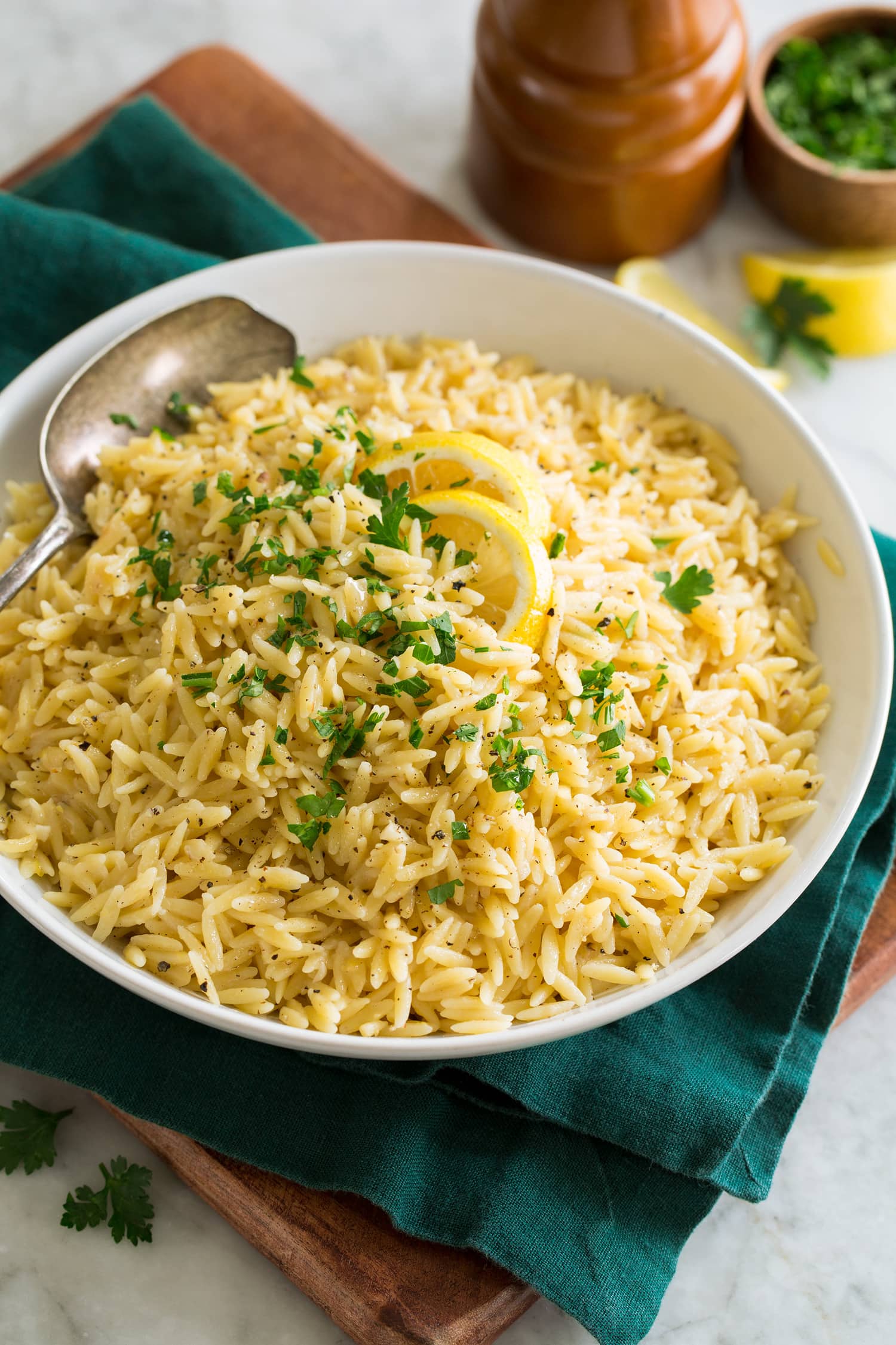 Bowl of lemon orzo set over a green cloth and a wooden tray.