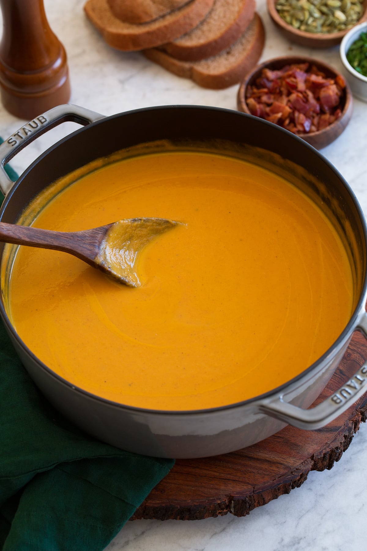 Pot of pumpkin soup with wooden ladle.