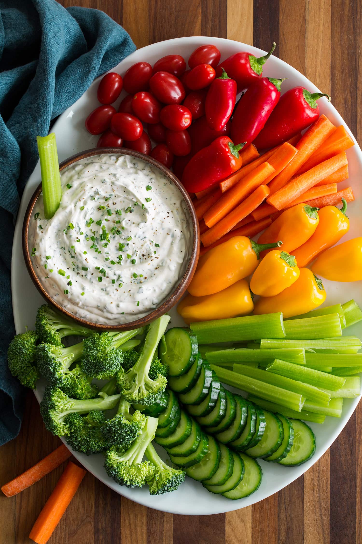 Ranch vegetable dip on a serving tray with a rainbow of chopped fresh vegetables.